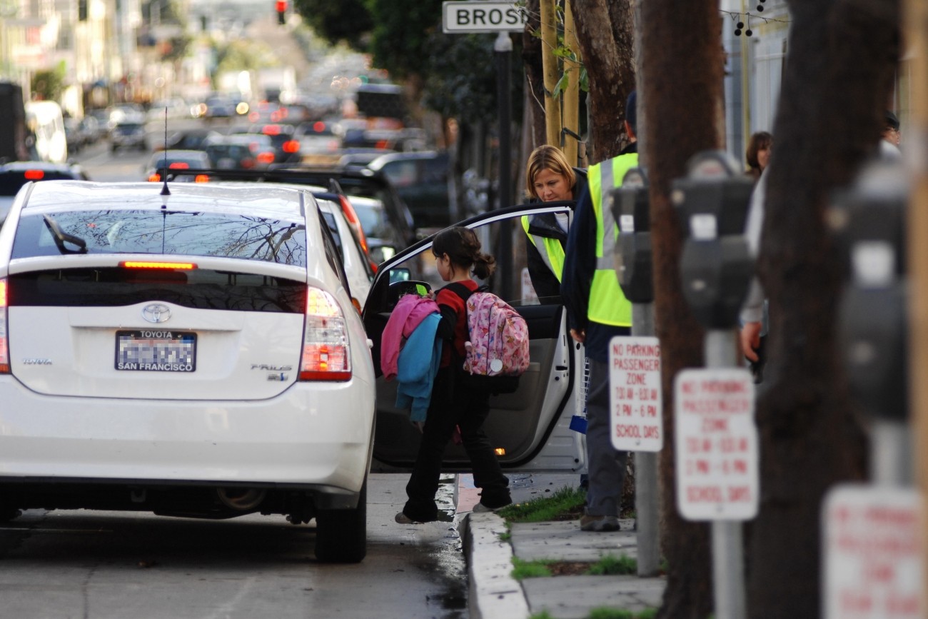 A child getting into a Prius with help from a school aide