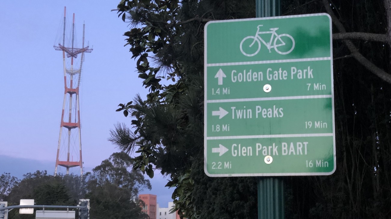 A bike wayfinding sign that gives directions to Golden Gate Park, Twin Peaks, and Glen Park BART