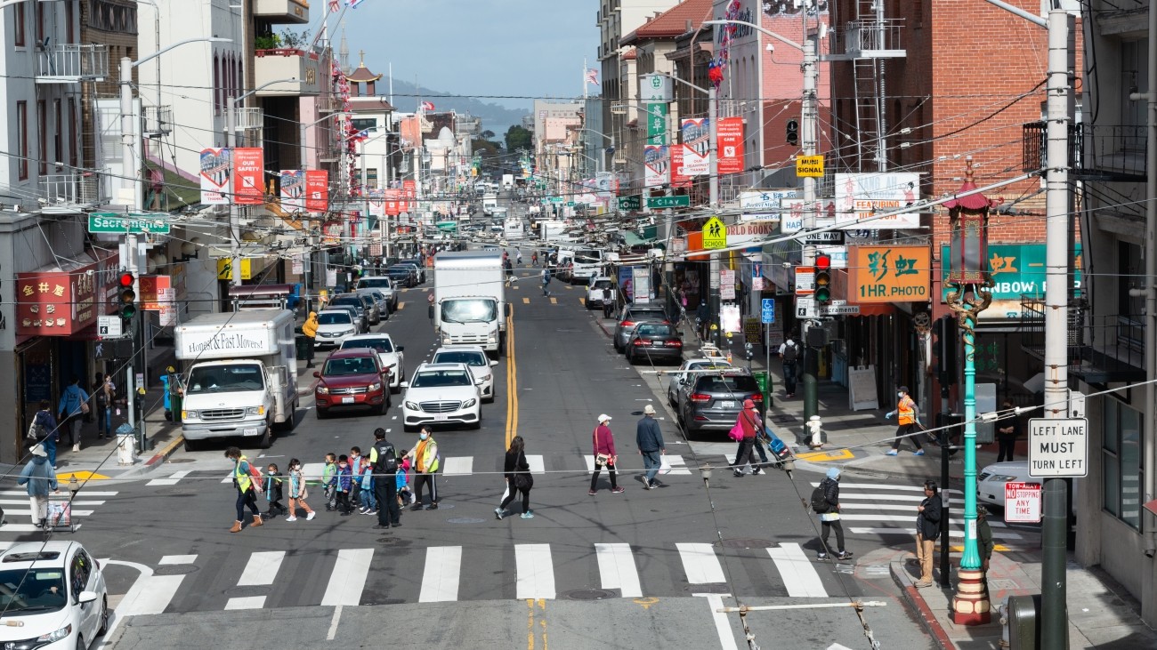 View of the Sacramento and Stockton Street intersection in Chinatown with pedestrians, trucks, and cars.