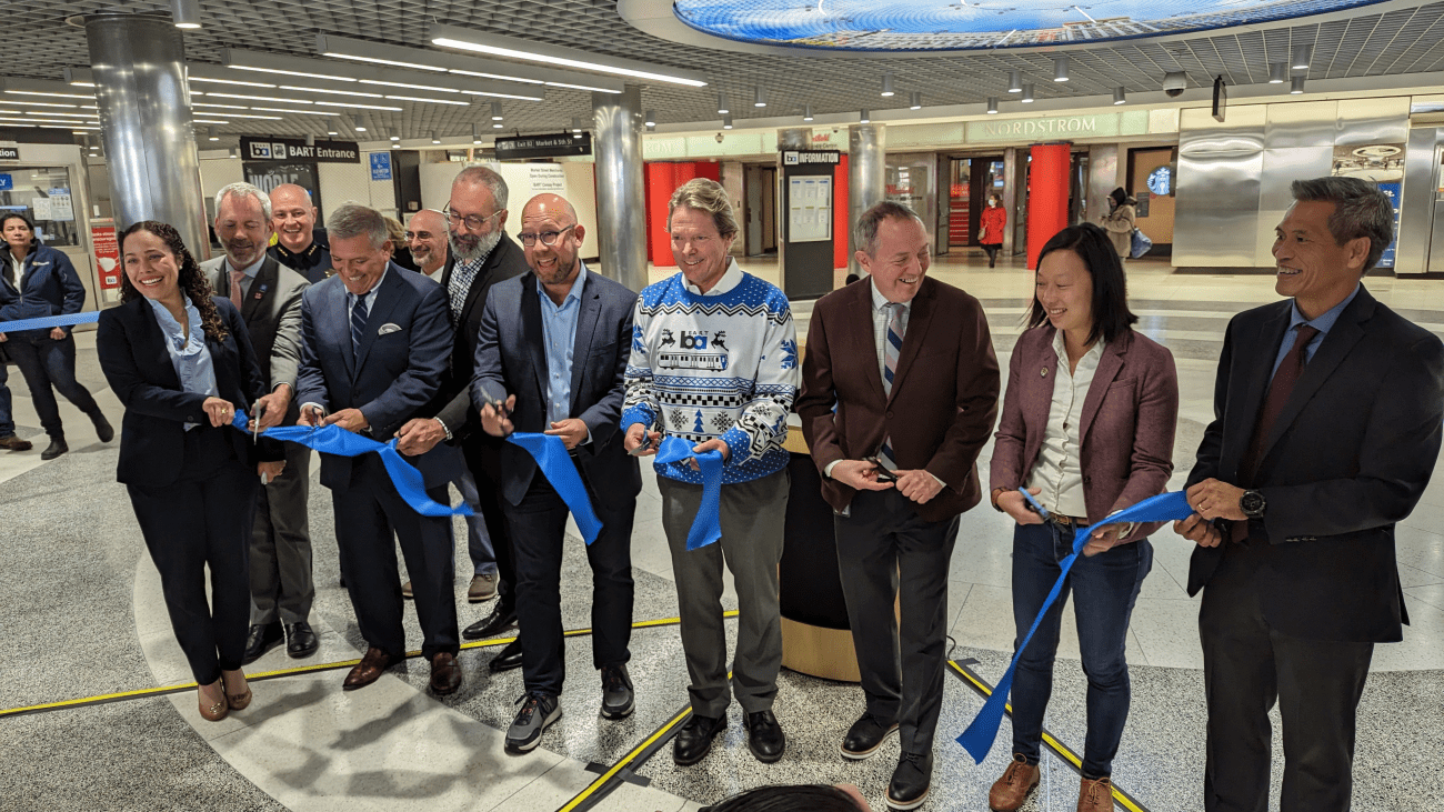 City and transportation officials cutting a blue ribbon at Powell Station