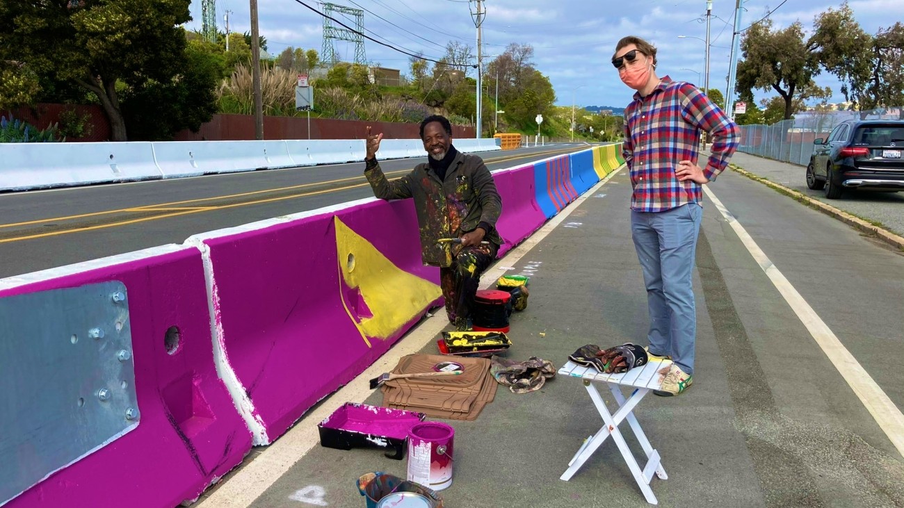 People standing by a mural in progress