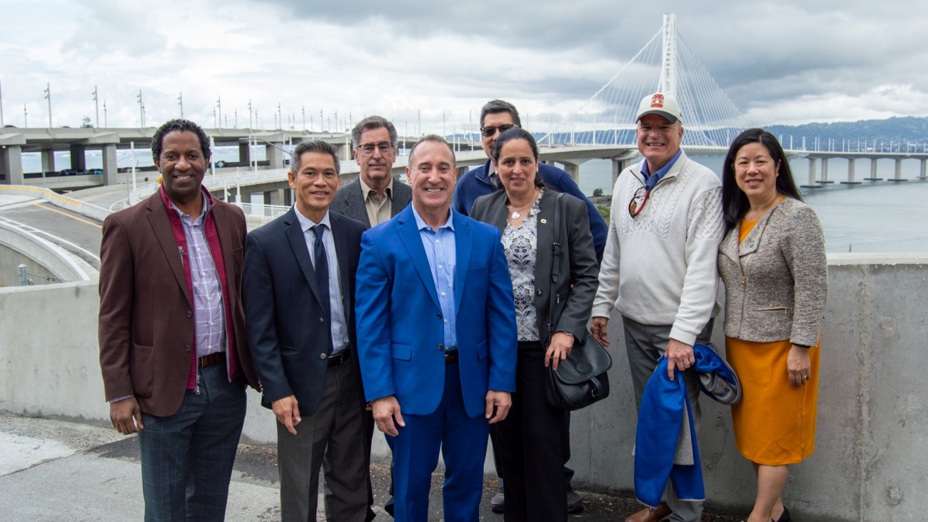 A group of people, including SFCTA Executive Director Tilly Chang and SFCTA Deputy Director for Capital Projects Carl Holmes, stand in front of the newly-finished Yerba Buena Island / I-80 Southgate Road and Interchange Project.