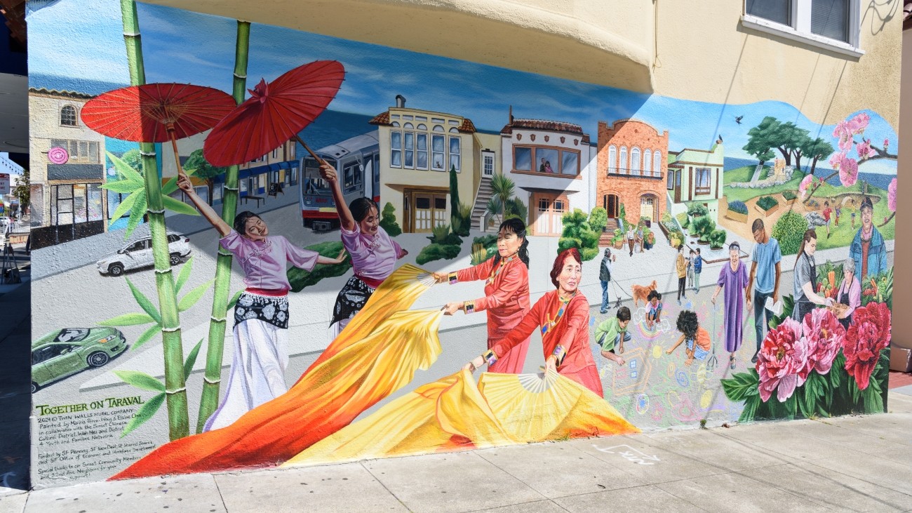 New community mural titled “Together on Taraval,”  featuring a L Tarval train, colorful dancers, youth, adults, and homes along Taraval Street