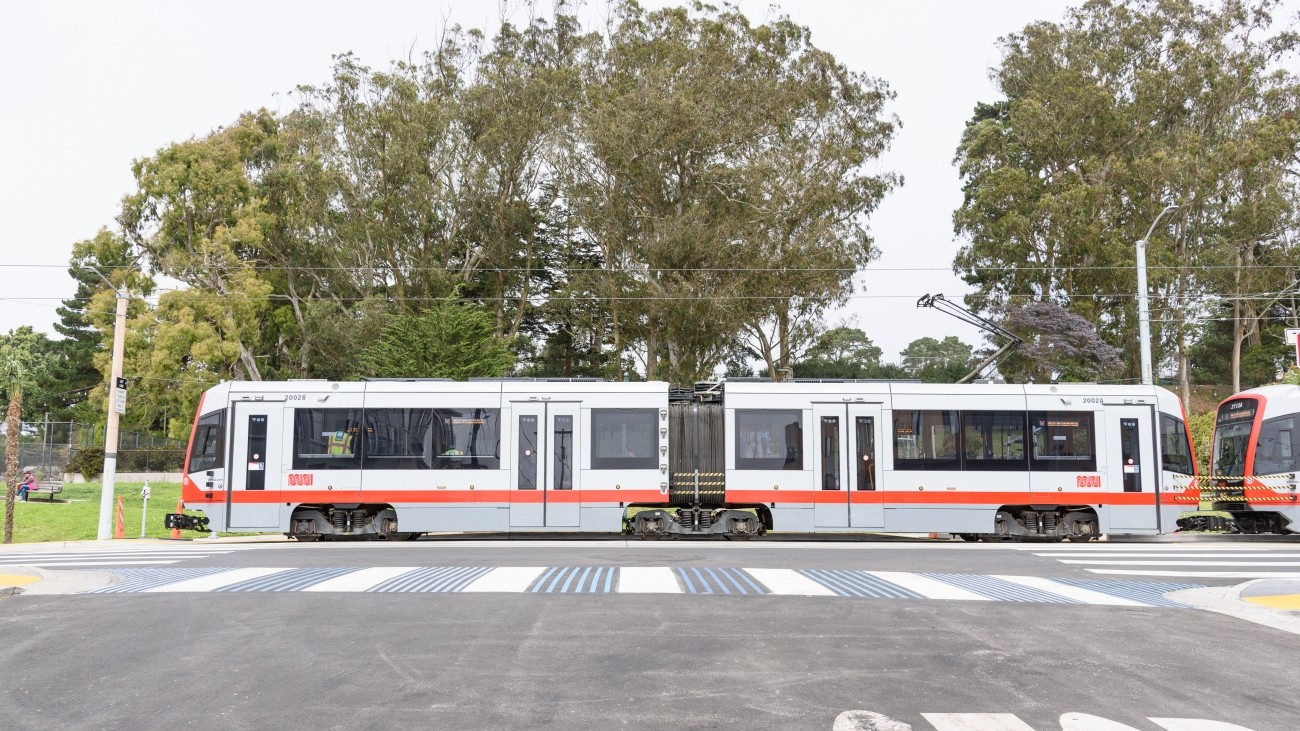 An L Taraval train with a decorated high visibility crosswalk in the foreground