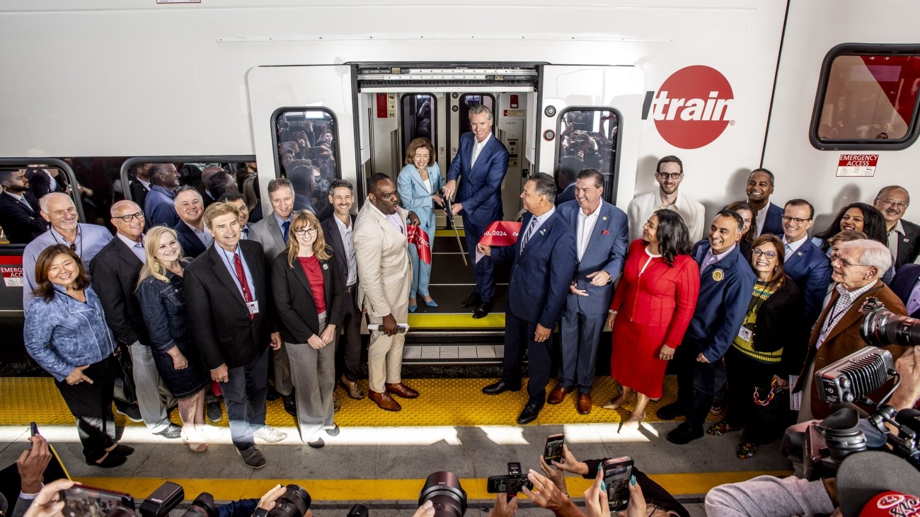 Elected officials and transportation staff gathered for a group photo in front of a new electric Caltrain train