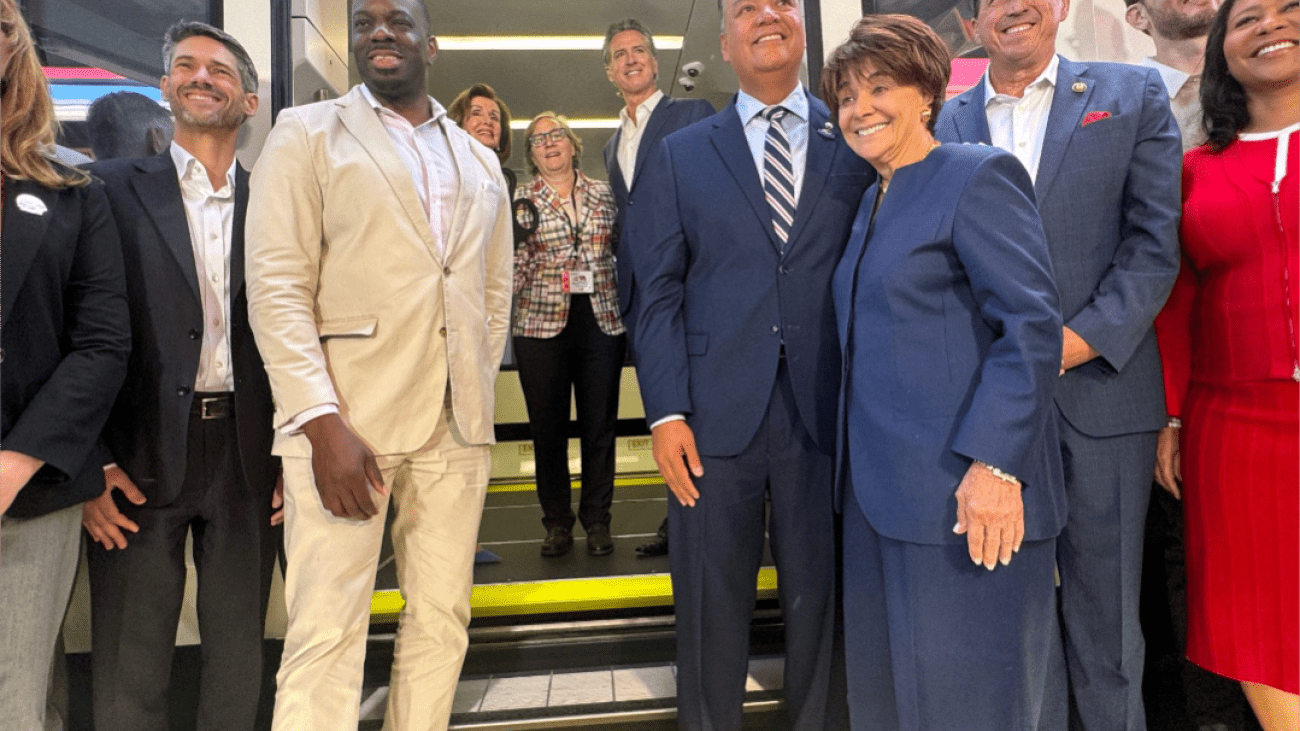 Elected officials and transportation staff gathered for a group photo in front of a new electric Caltrain train