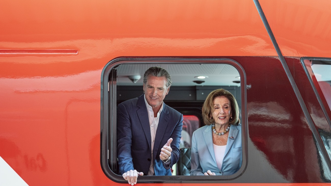 Governor Gavin Newsom and Speaker Emeritus Nancy Pelosi by a window in Caltrain vehicle