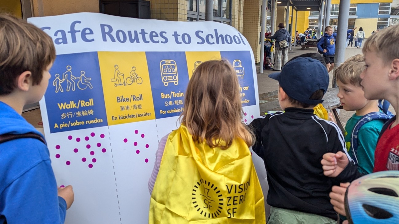 Students gathered at a posterboard to share what mode of transportation they used to get to school