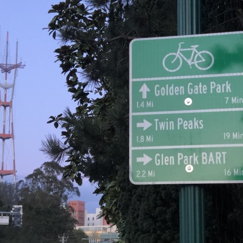 A bike wayfinding sign that gives directions to Golden Gate Park, Twin Peaks, and Glen Park BART