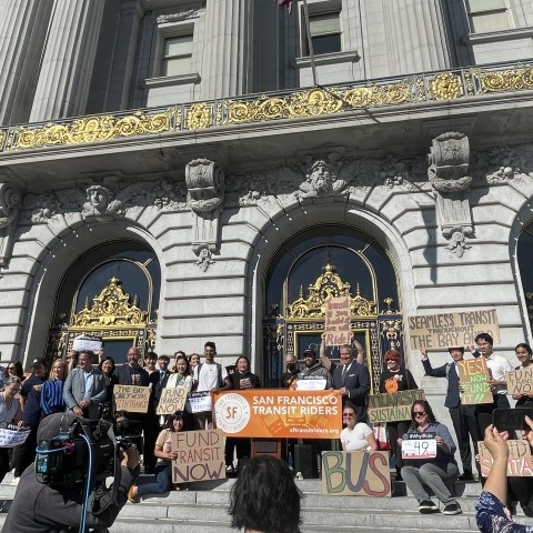 Local city and transportation officials, community advocates and leaders gathered in front of City Hall holding signsand 