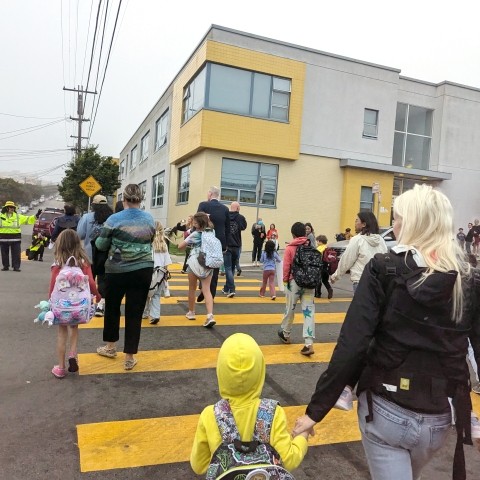 Parents and students in a crosswalk on their way to school