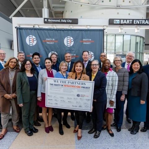 Transportation officials gathered together and holding a signed Equity In Infrastructure pledge