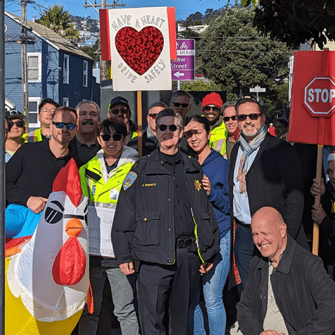 Staff from transit agencies, SF Public Works, SFPD, and community members standing by new traffic signal at Alemany and Rosseau