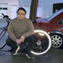 A person squatting with a bike behind them 